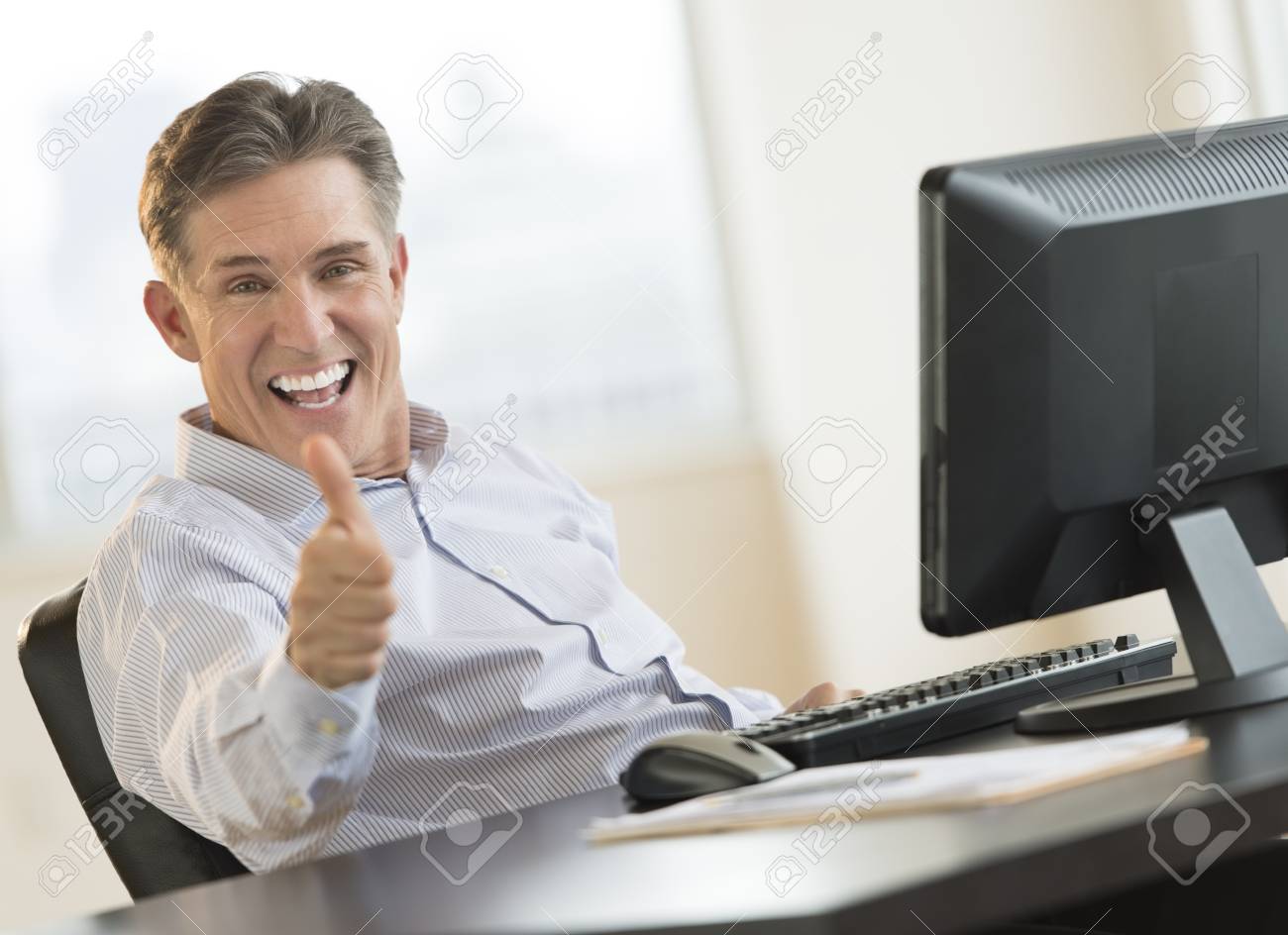 22079719-excited-mature-businessman-gesturing-thumbs-up-while-sitting-at-computer-desk-in-office.jpg